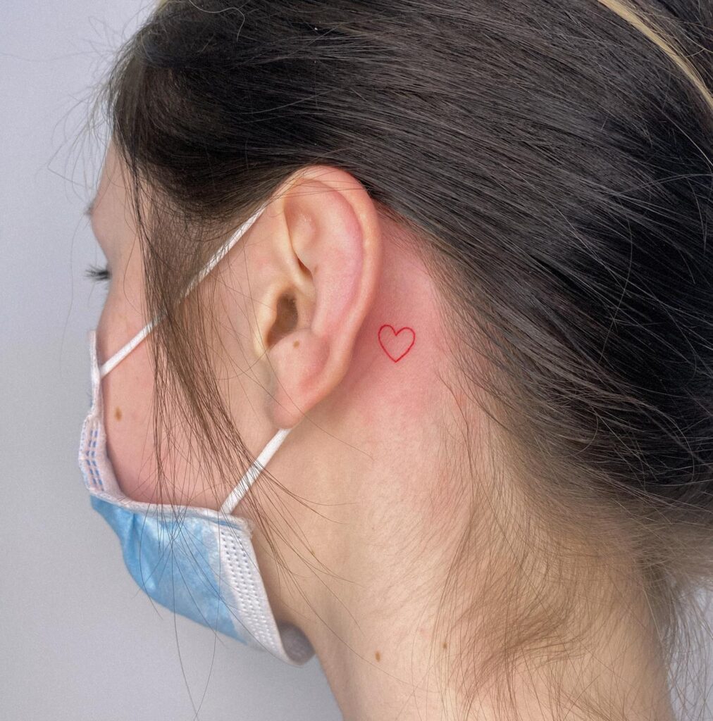Fine line red outline heart tattoo behind the ear