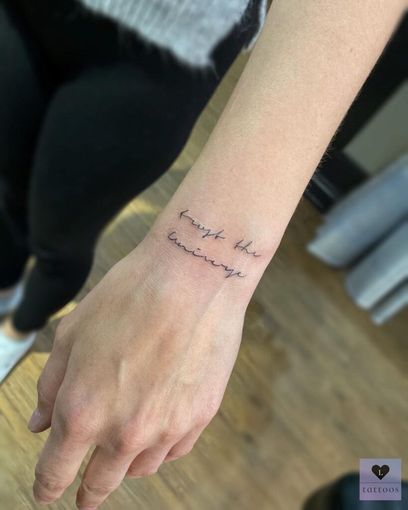 Fine line script trust the universe outer wrist tattoo, small design