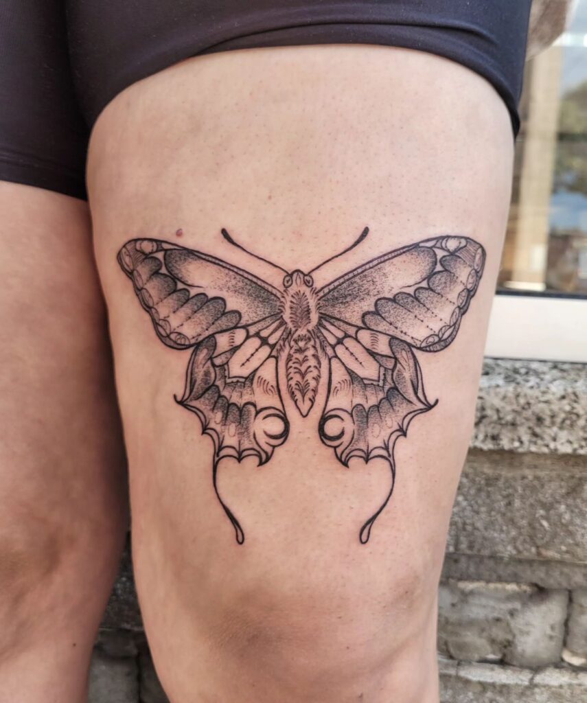 Fine line single needle butterfly tattoo on thigh subtle detail
