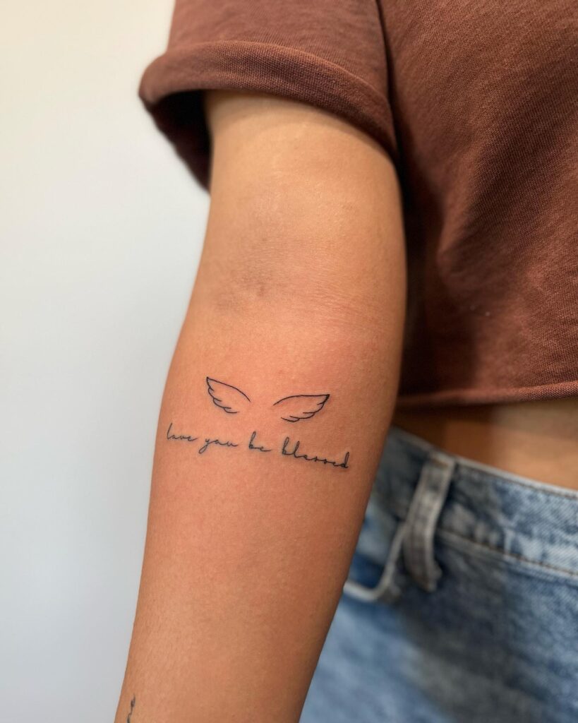 Fine Line Small Wing Tattoo with Cursive Lettering 'Love You, Be Blessed' Below the Inner Elbow: Divine Blessing