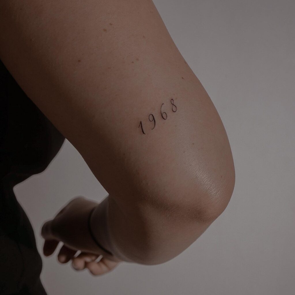 Fineline '1968' Tattoo on the Back of the Elbow: Timeless Tribute