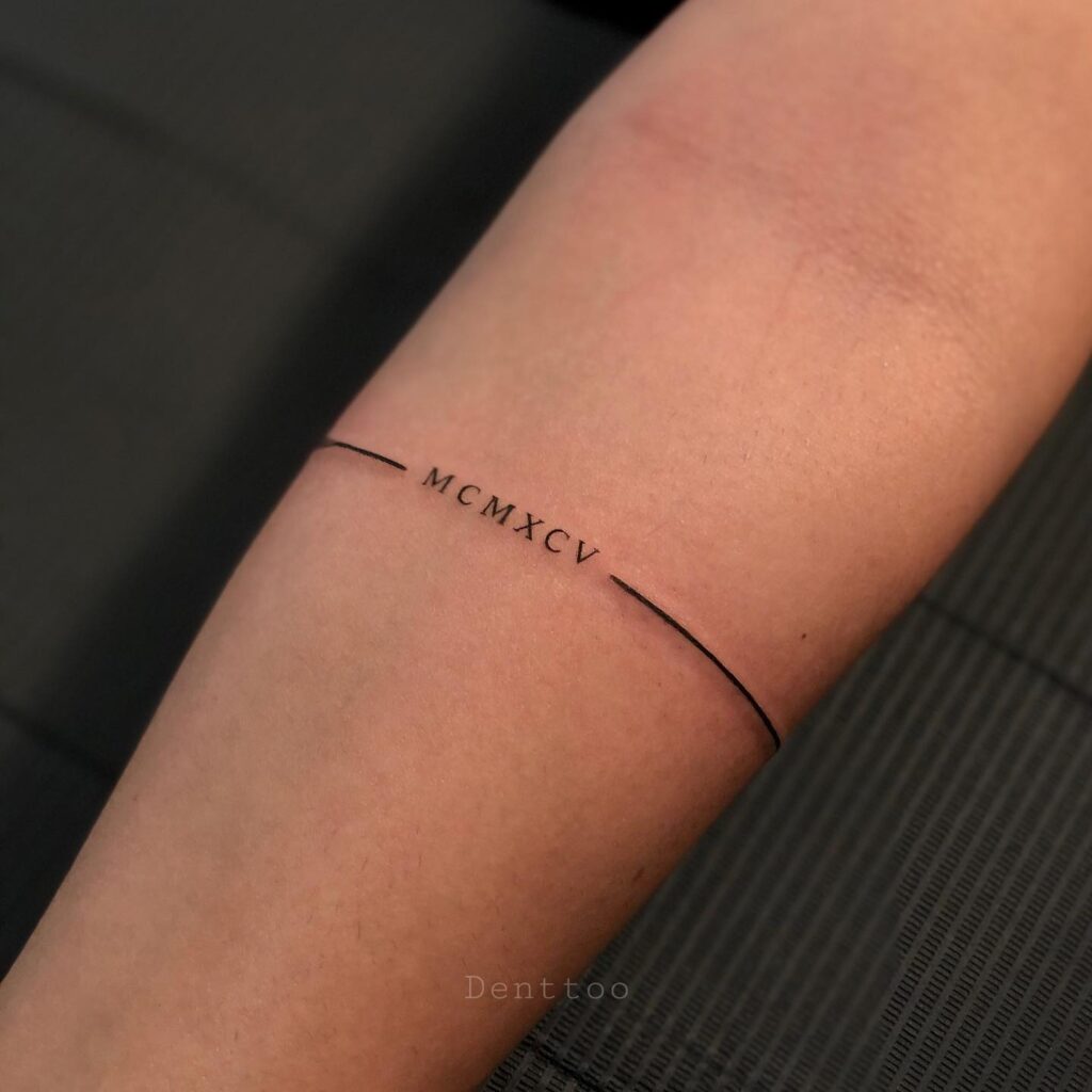 Fineline Band Tattoo Engraved Around the Forearm with 'MCMXCV': Timeless Elegance