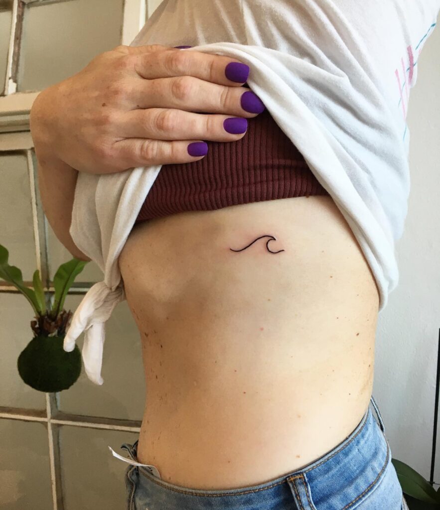 Fineline cute wave tattoo creating a serene scene on the rib wave whispers