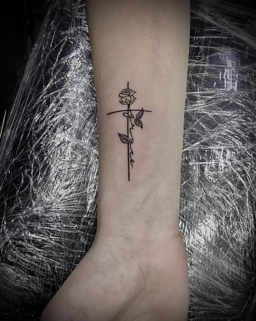 Fineline grace tattoo with cross and rose on wrist a delicate expression