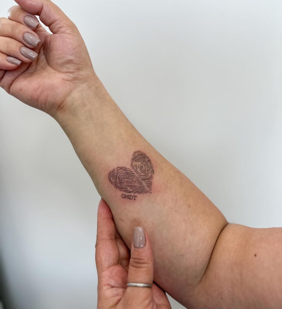 Fingerprint Heart Tattoo on the Forearm with GMDT Lettering: Heartfelt Identity
