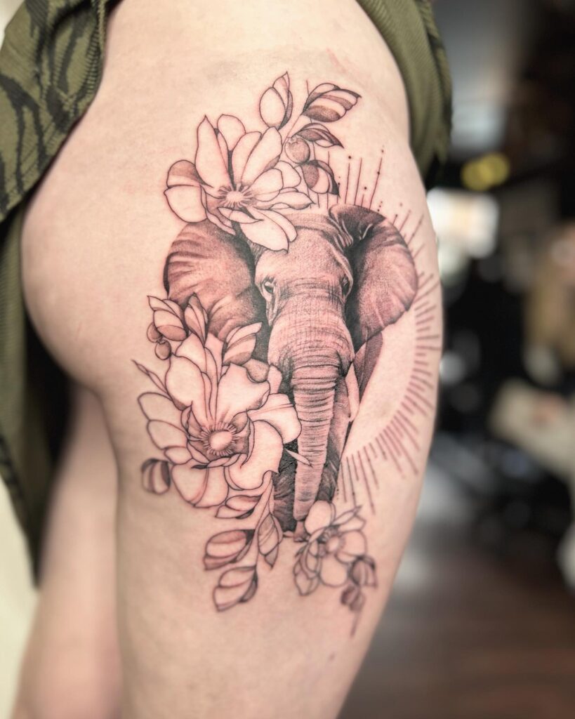 Flowers, half sun, and elephant side view tattoo for women: thigh artistry