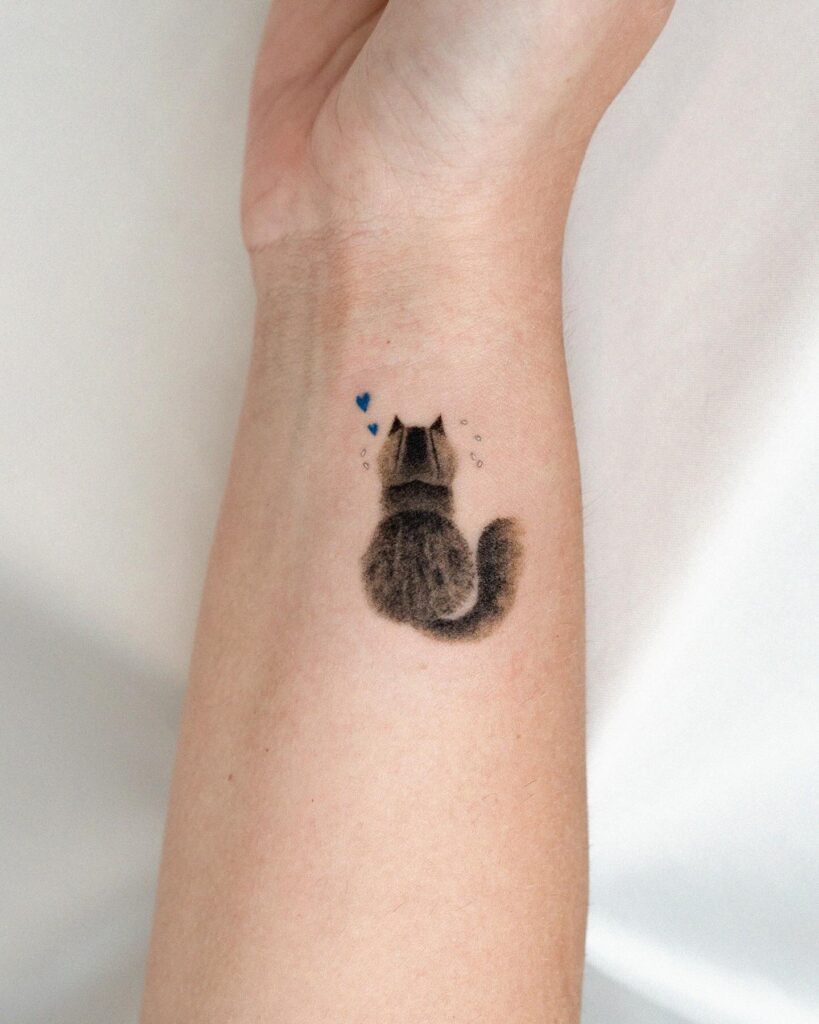 Fluffy cat wrist tattoo with floating hearts tribute to a beloved pet