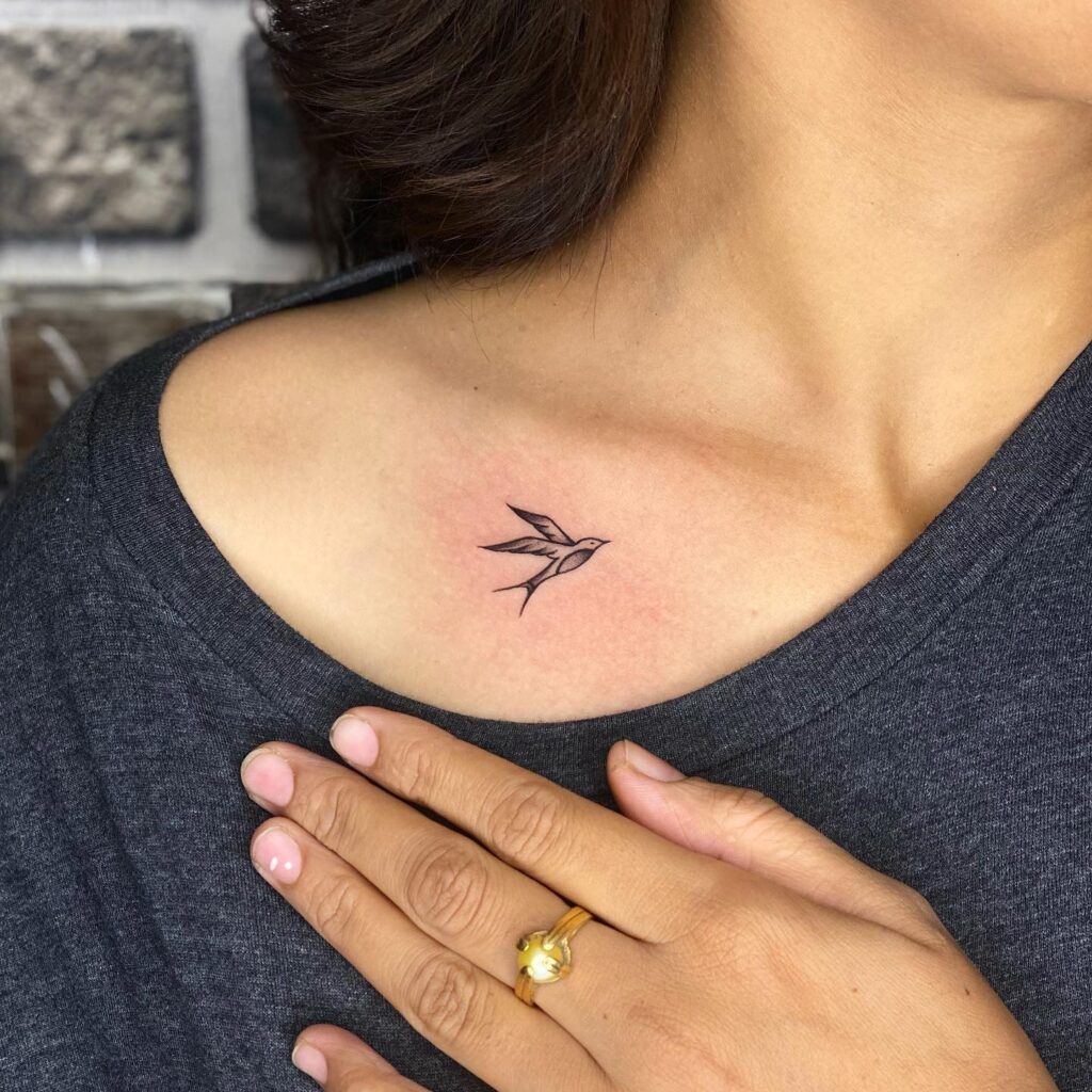 Flying bird side view tattoo on the collarbone, a small and simple avian accent free as a bird