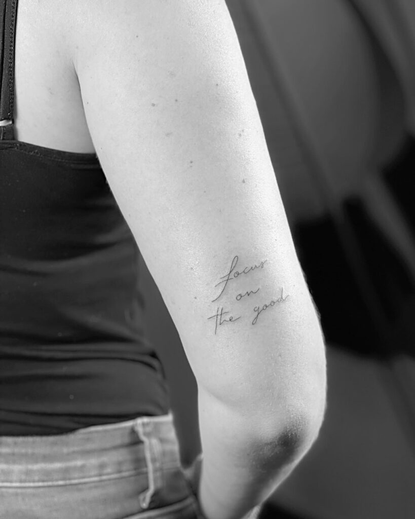 'Focus on the good' script lettering tattoo back of arm above elbow, a daily reminder: Positive focus