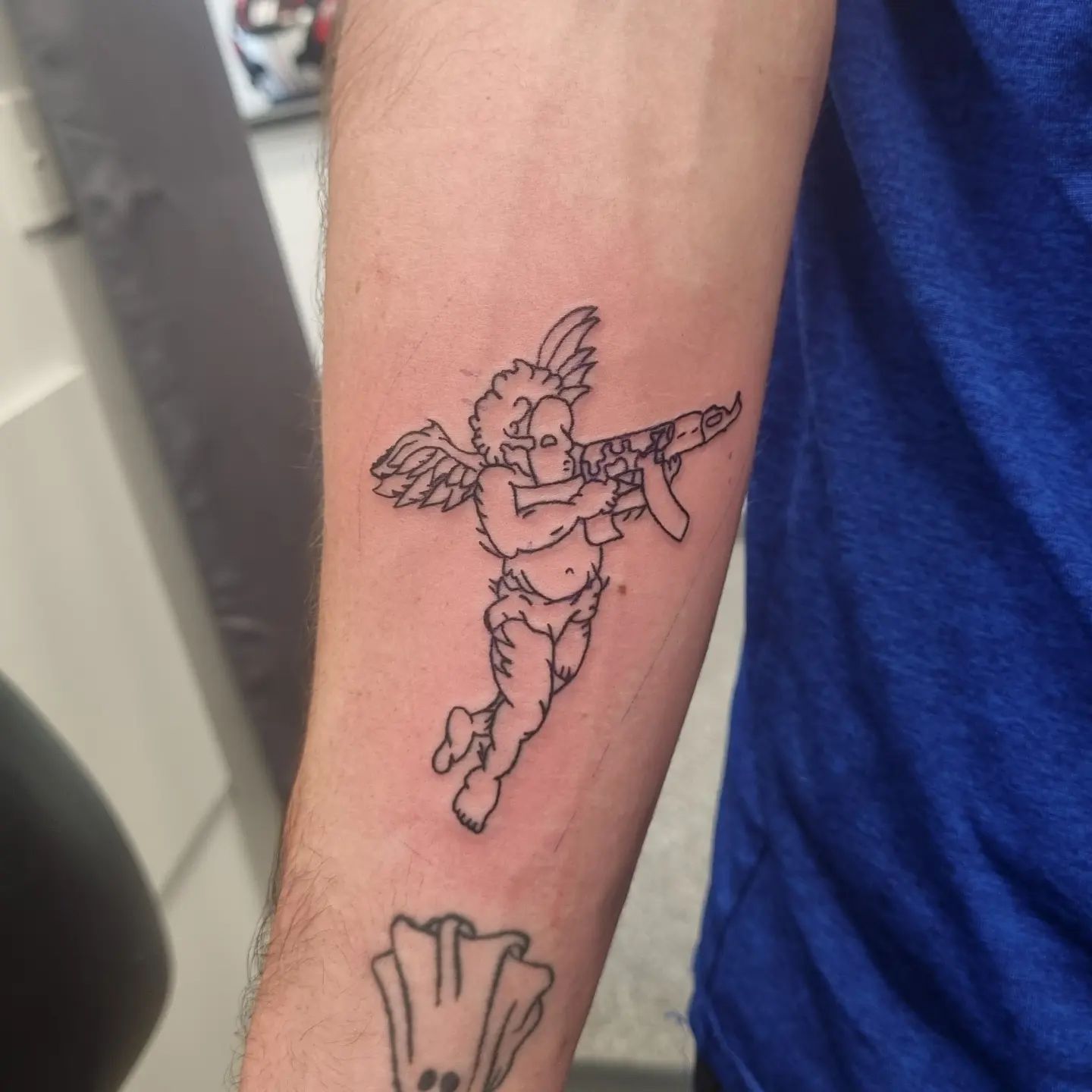 Forearm outliner angel with gun tattoo for male and female Forearm outliner angel with gun tattoo for male and female
