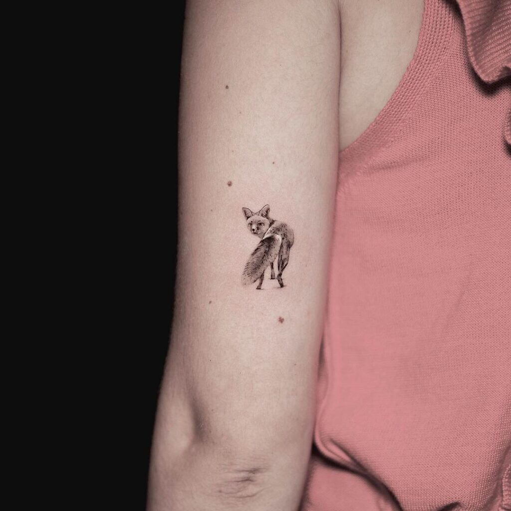 Fox tattoo above the elbow graceful look back in grey