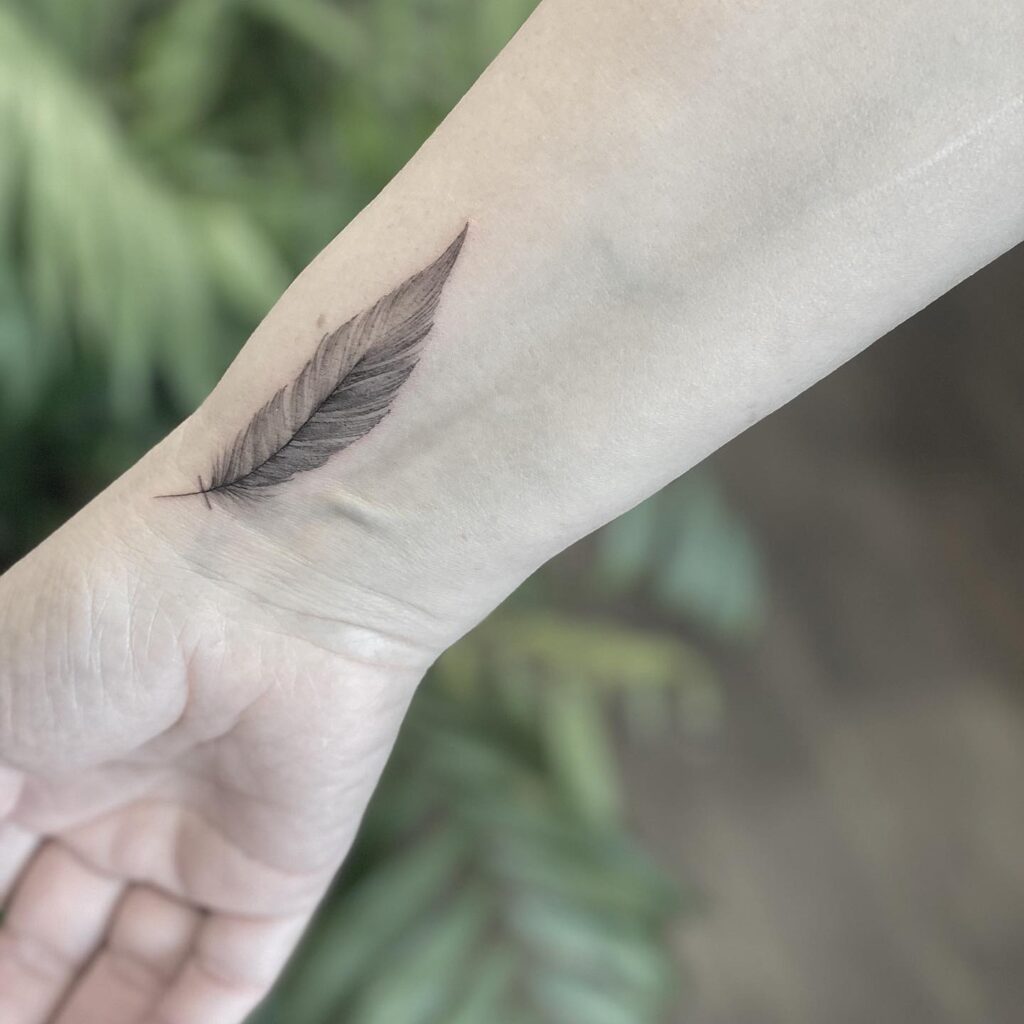 Freehand Feather Tattoo on the Wrist Showcasing Black and Grey Features for a Boho Vibe Feathery Whimsy