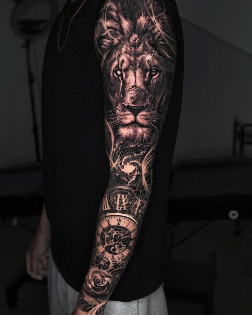 Full sleeve blackwork ink tattoo with upper arm covered by a lion face and lower sleeve adorned with a clock timeless majesty