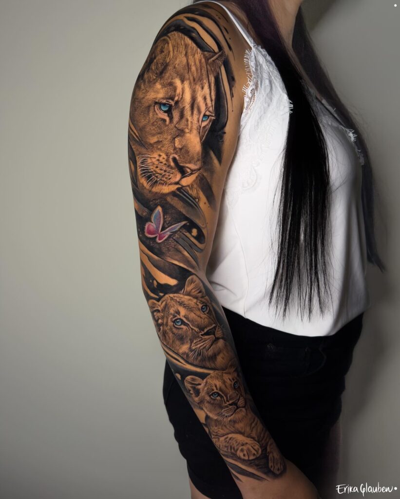 Full sleeve lioness and cubs tattoo with colorful butterfly accent: family bonds