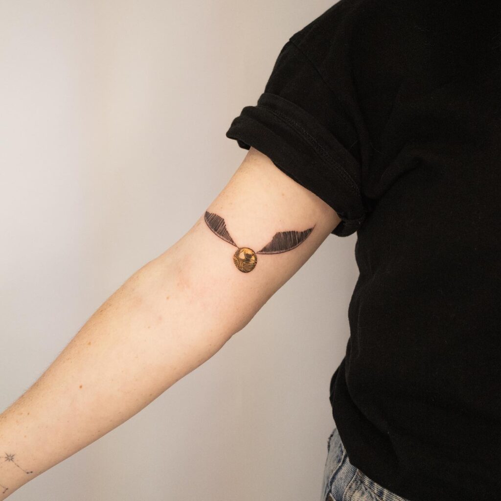 Golden snitch tattoo ideas capturing magic above the inner elbow