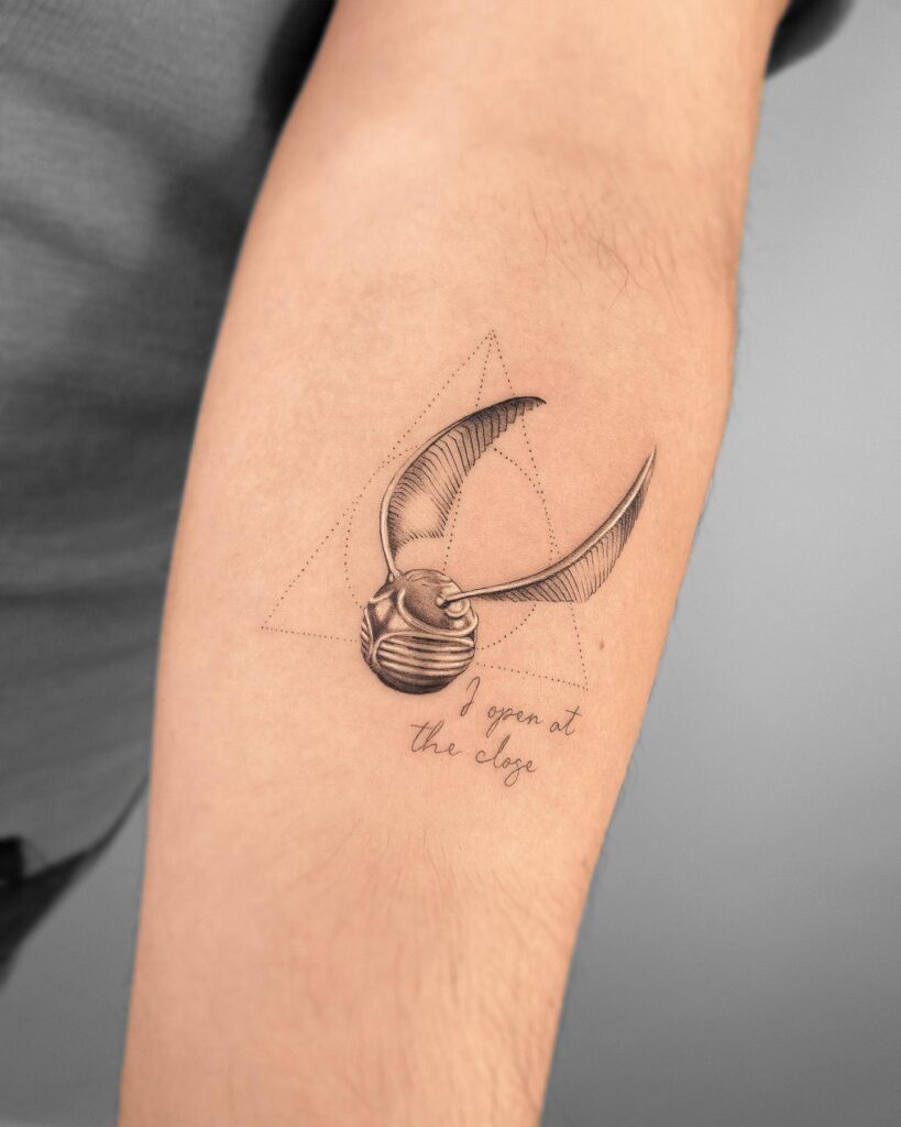 Golden snitch tattoo with 'I open at the edge' lettering a spellbinding combination