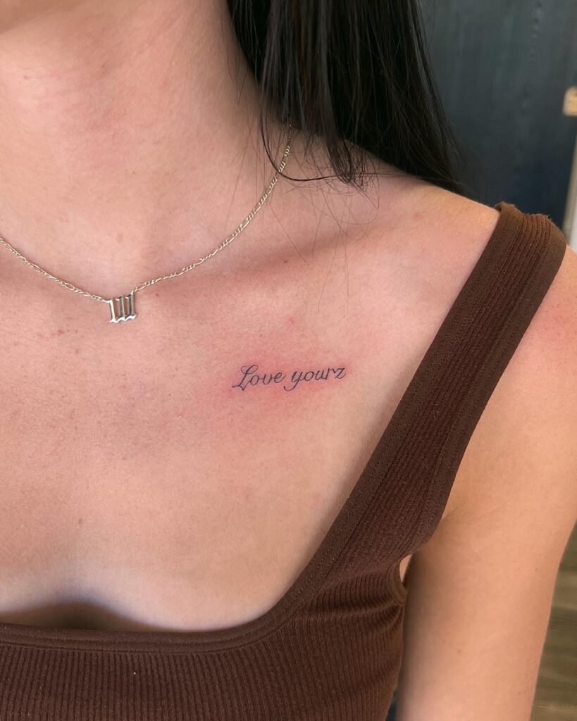 Gorgeous script 'Love Yourz' tattoo on the collarbone, stylishly empowering self-love proclamation