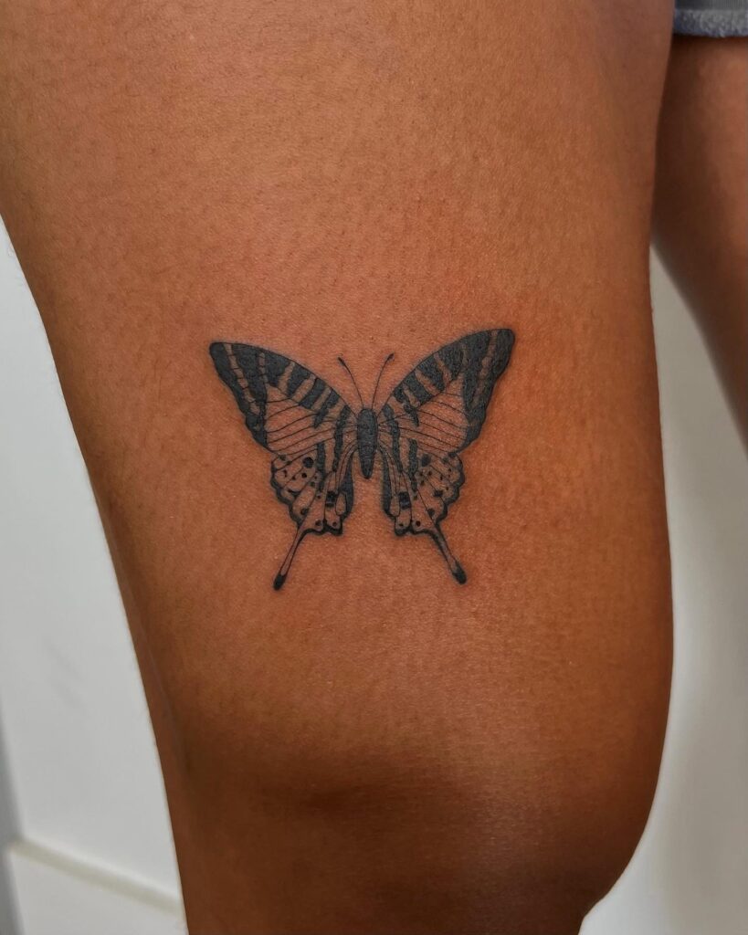Graceful swallowtail black butterfly tattoo on thigh