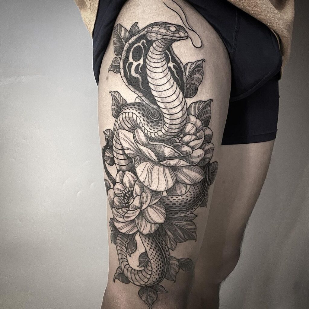Grey and black realistic cobra tattoo wrapping around flowers head held high