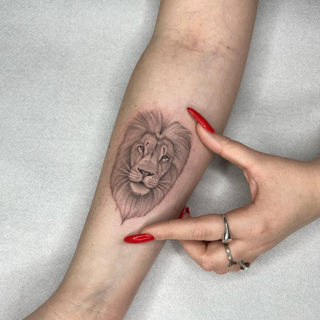 Grey color micro lion tattoo on the forearm: micro majesty