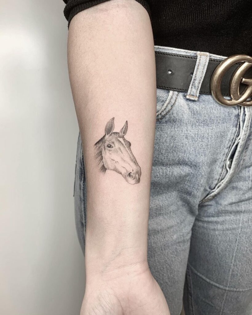 Grey-shaded horse face tattoo on the inner forearm graceful equine