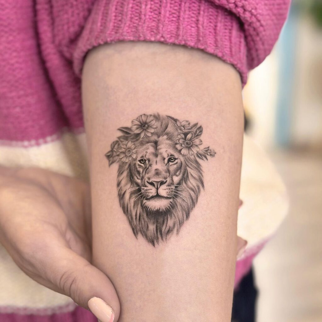 Grey shaded realistic lion face with flowers above inner elbow: elbow elegance