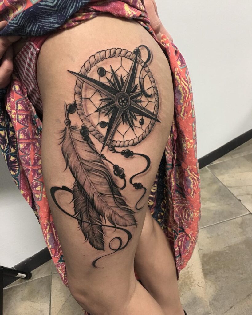 Guided dreamcatcher, compass, and feather thigh tattoo for women a journey of symbolism