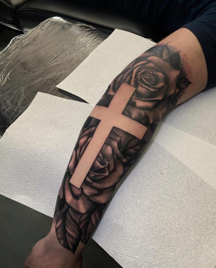 Half sleeve tattoo on the outer forearm for men cross with roses - a bold statement