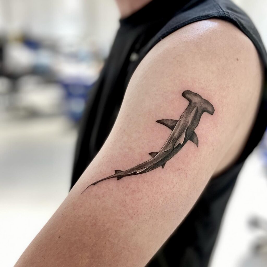 Hammerhead shark tattoo with 3D shading and dark contrast on upper arm