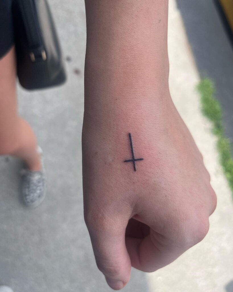 Handcrafted faith small cross tattoo on a girl's hand
