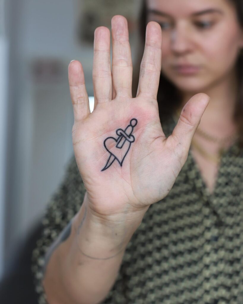 Heart and Dagger Inner Hand Tattoo on the Palm for Females Outlined for a Chic and Edgy Look: Hearts Edge