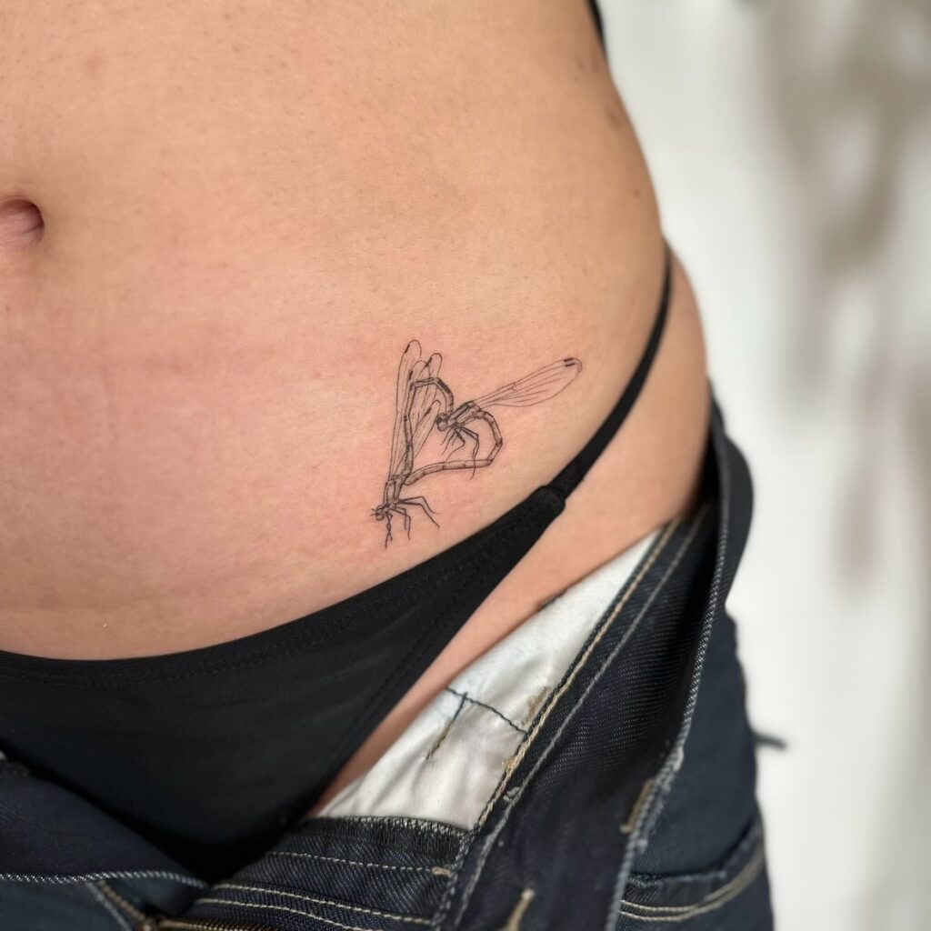 Heart-Shaped Damselfly Tattoo on the Hip Symbolizing Love and Connection