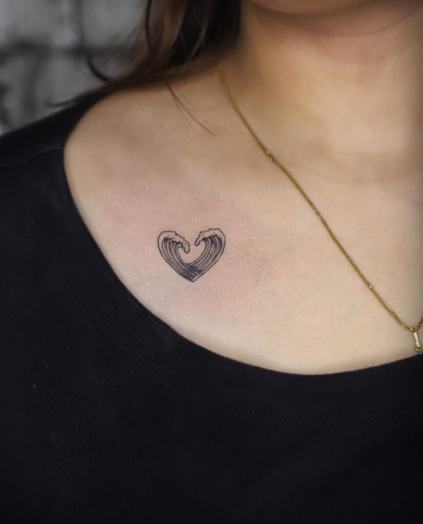Heart-shaped sea wave tattoo on the collarbone, a symbol of fluid love ocean's embrace