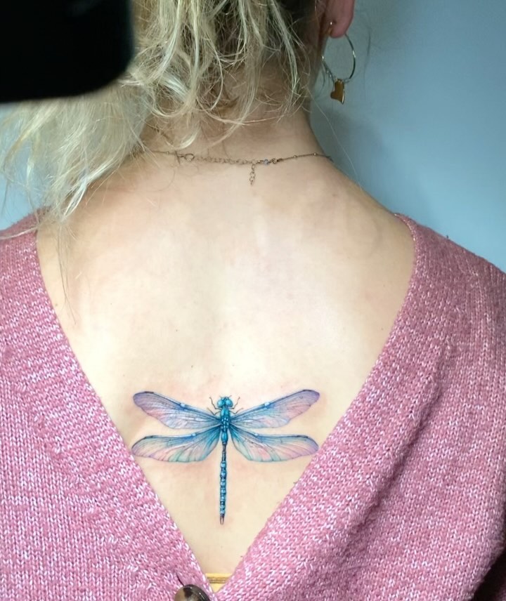 Hyper-Realistic Dragonfly Upper Back Tattoo with Vibrant Blue and Pink Hues