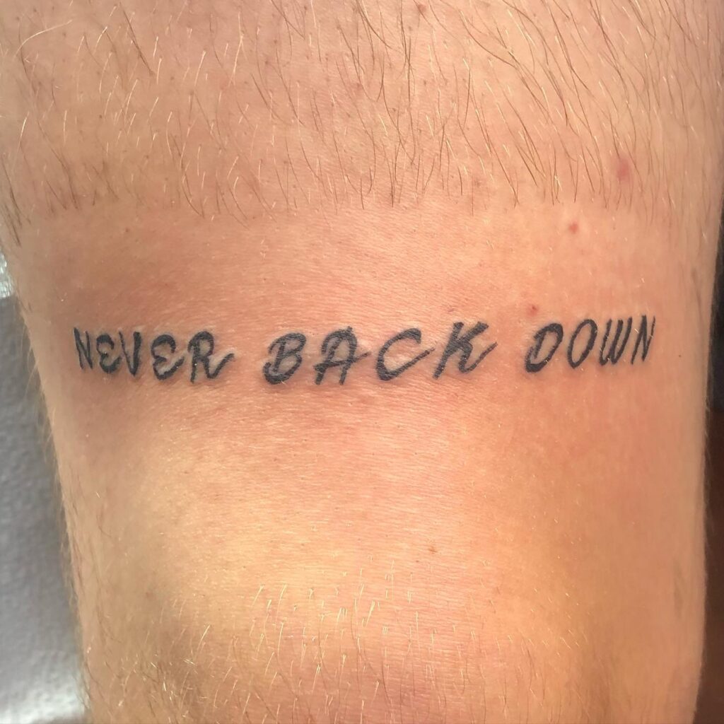 Inked inspiration never back down text tattoo above the knee