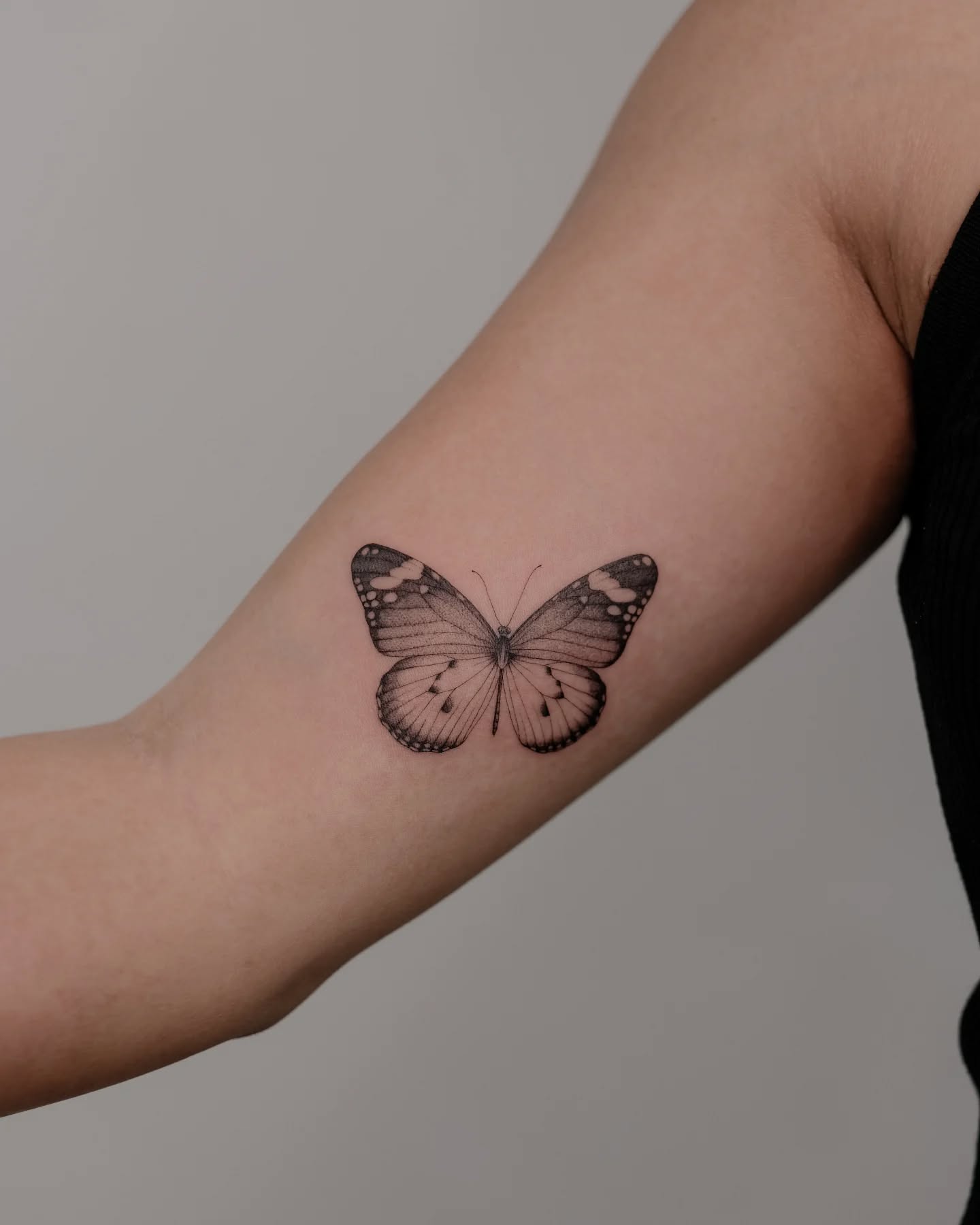 Inner bicep butterfly tattoo with fine lines and deep symbolic meaning
