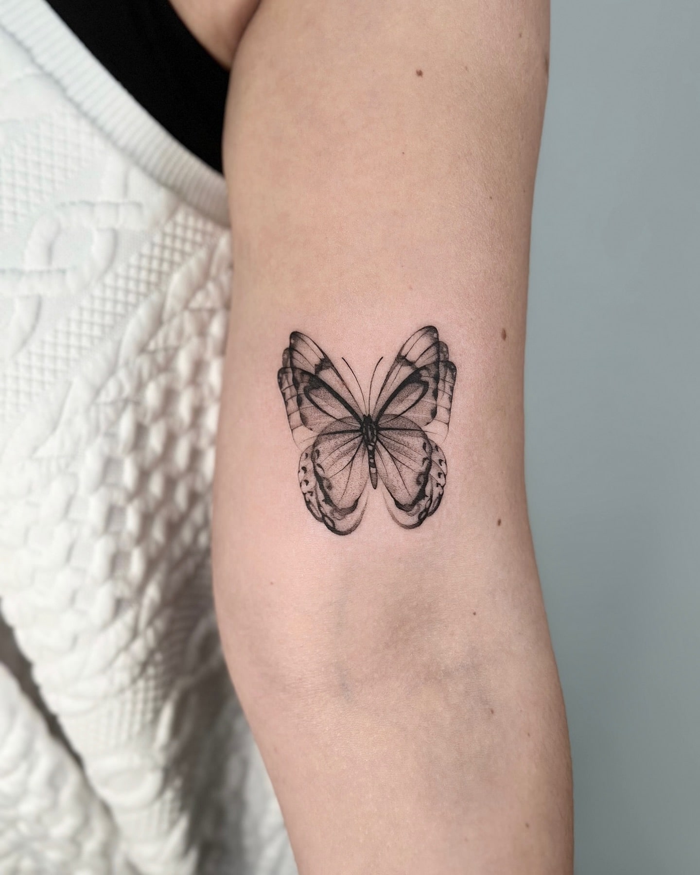 Intricate butterfly upper arm tattoo with elegant linework