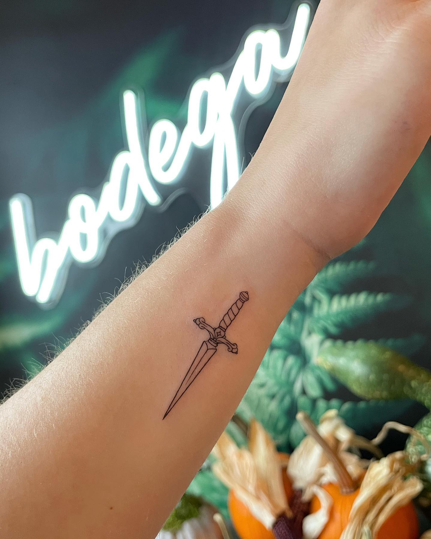 Intricate Fine-Line Dagger Tattoo on Wrist Symbolizing Strength & Resilience