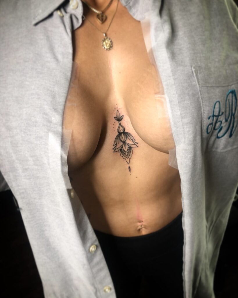 Intricate lotus-inspired sternum tattoo with ornamental spiritual details