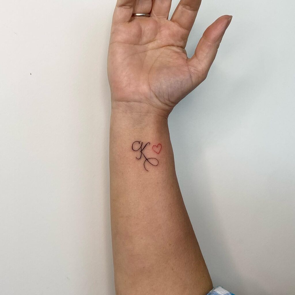 K calligraphy letter with red outline heart tattoo on the wrist