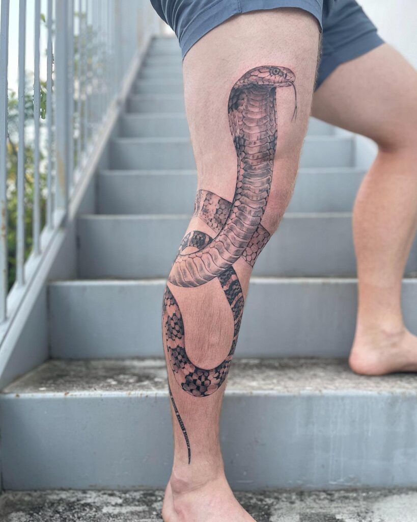 King cobra tattoo around the leg with head up on the thigh: regal coil