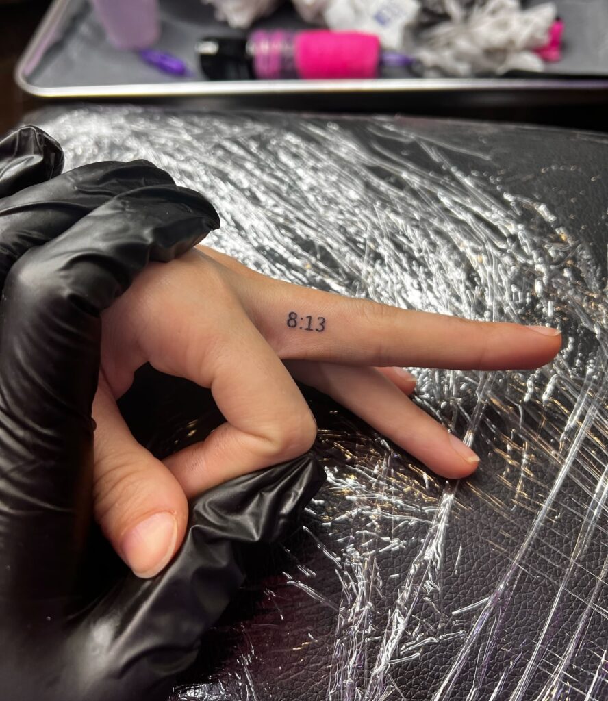 Left hand 8:13 on the side of the middle finger, a fine line tiny tattoo timeless reminder
