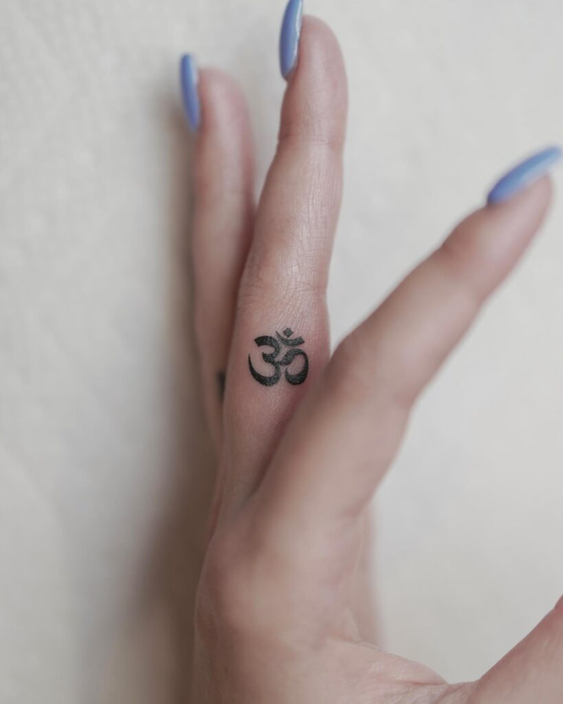 Left hand side finger om symbol tattoo, boldly inked in black om harmony