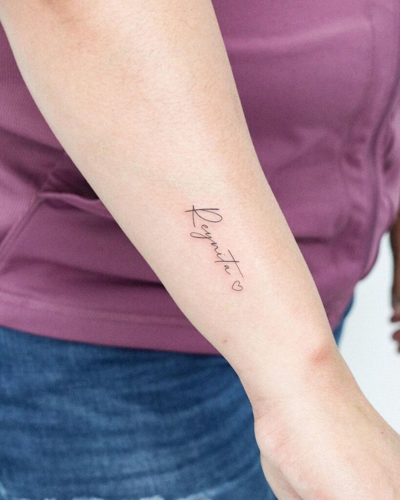 Lettering reynita name tattoo with heart outline on side wrist
