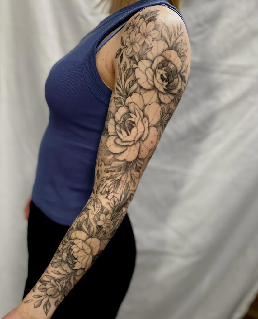 Lifelike black and grey floral tattoo sleeve with intricate botanical elements