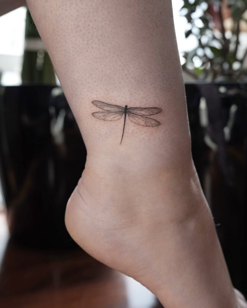 Lifelike Dragonfly Ankle Tattoo Representing Transformation and Change