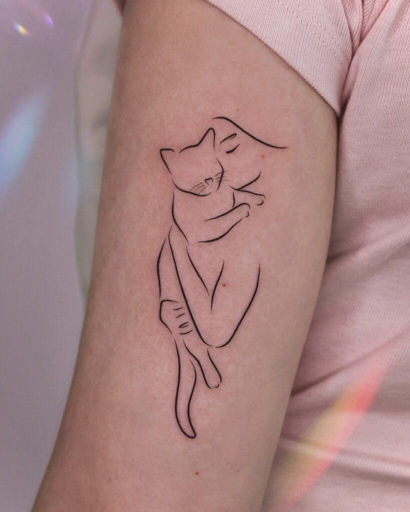 Line art cat and person hug tattoo on upper arm symbolizing bond