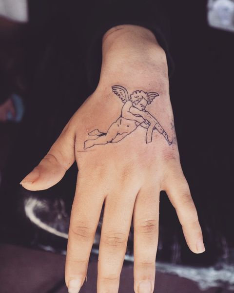 Lined wrist angel with gun tattoo with image