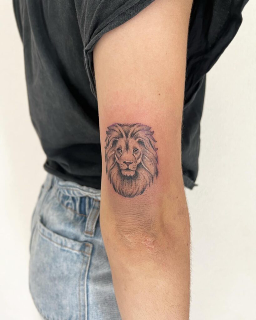 Lion face back of the above elbow tattoo: cool elegance
