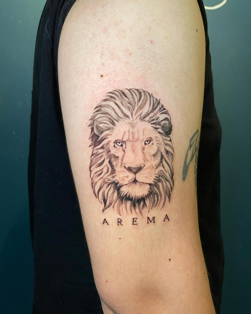 Lion face tattoo with 'Arema' word lettering on the upper arm: calm majesty
